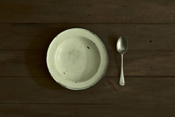 piatto smaltato e cucchiaio su tavolo di legno - affamato foto e immagini stock