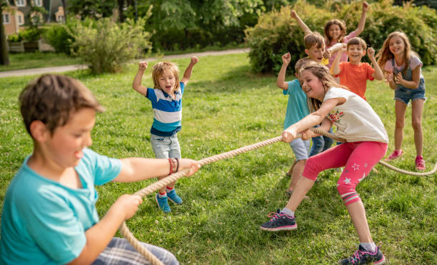 istock Playful children are pulling a rope in park 1257843619