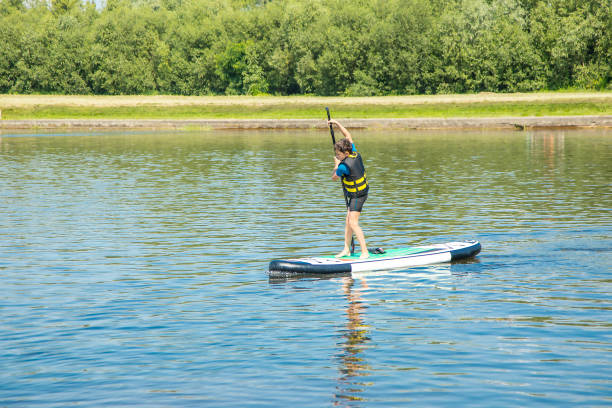 A paddler-boarder. Photo of 10-year-old Boy rowing on a standing Board. Healthy lifestyle. Water sports, SUP surfing tour in adventure camp on active summer beach holiday. Healthy active lifestyle A paddler-boarder. Photo of 10-year-old Boy rowing on a standing Board. Healthy lifestyle. Water sports, SUP surfing tour in an adventure camp on active summer beach holiday. Healthy active lifestyle paddleboard surfing water sport low angle view stock pictures, royalty-free photos & images