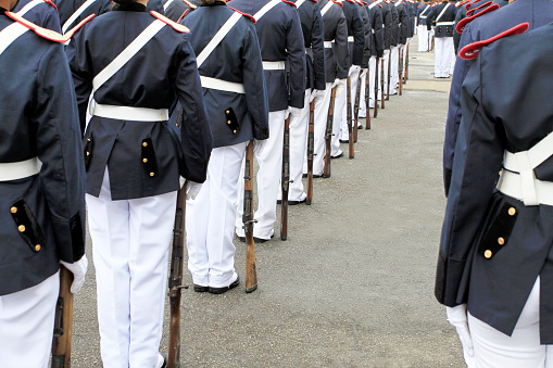 Uniformed honor guards standing at attention in a formal setting with ceremonial rifles.