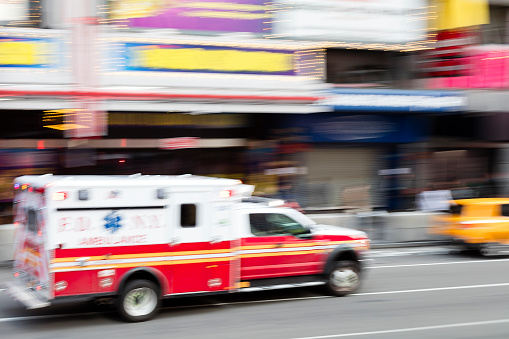 Motion blurred ambulance speeding down street in New York City, USA.