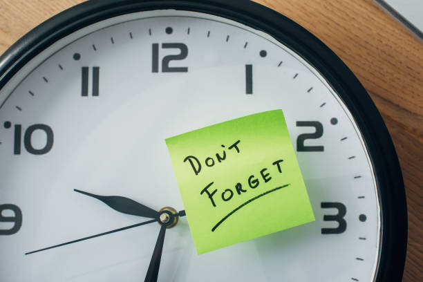 istock Top view of sticky note with dont forget lettering on clock on table 1257851888