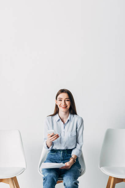 istock Smiling employee looking at camera while holding smartphone and resume in office 1257851917