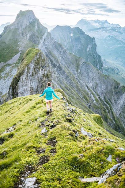 Trail runner ascends high mountain ridge Above distant mountains and valleys schwyz stock pictures, royalty-free photos & images