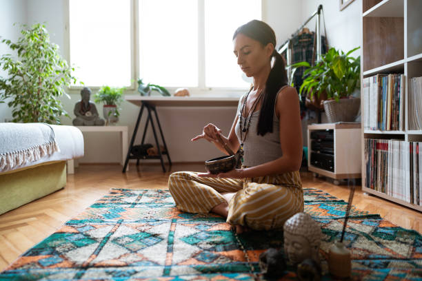 istock Yogi woman relaxing at home while meditating and using meditation bell 1257852183