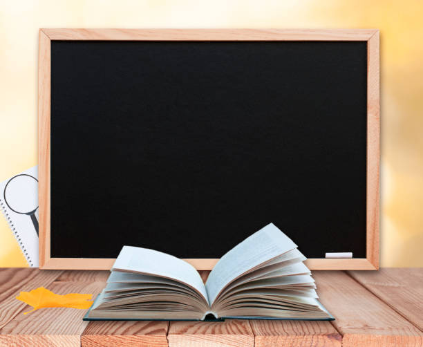 istock Open book with maple leaf on the wood table top with blackboard, magnifying glass, notebook 1257852281
