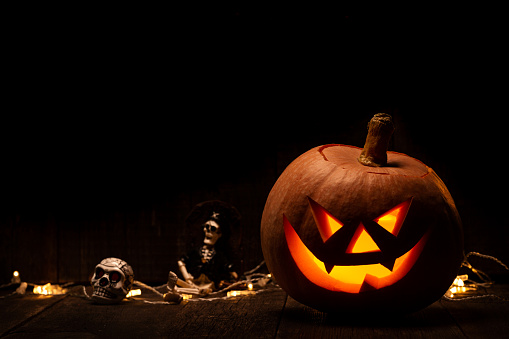 Halloween pumpkin with scary face on wooden background. Jack-o-lantern on black background. Celebration autumn holiday