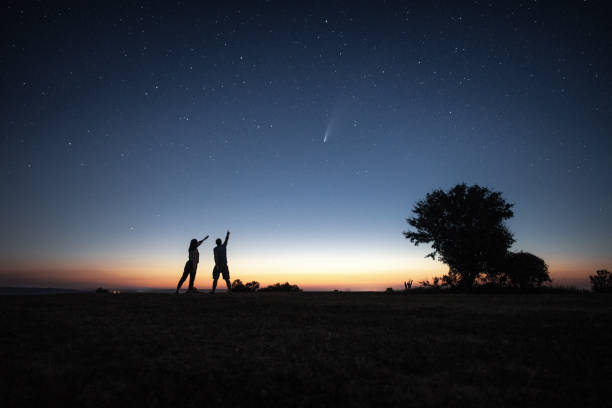 istock Young couple watching the Neowise comet under the bright night sky 1257859725
