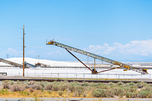 Salt Lake City, Utah landscape with desert salt mining factory at lake Bonneville with piles of white mineral and industrial equipment