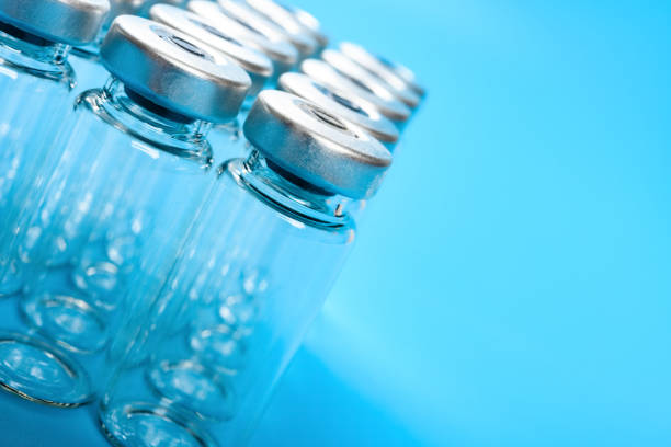 garrafas de vacina vazias em fundo azul com espaço de cópia - transparent ideas lid glass - fotografias e filmes do acervo