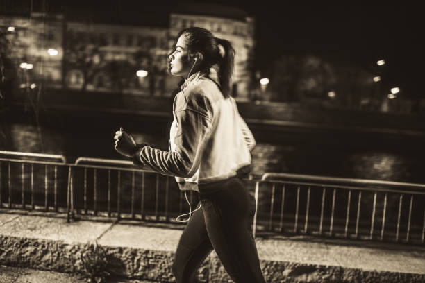 Young female athlete running on sidewalk near river