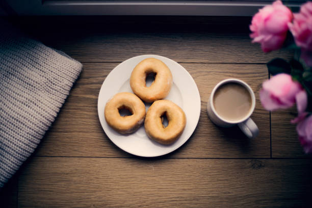 Fresh donuts in white plate on wooden background