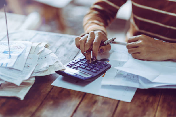 istock Woman counting finances salary, using calculator, people pressing. 1257882732