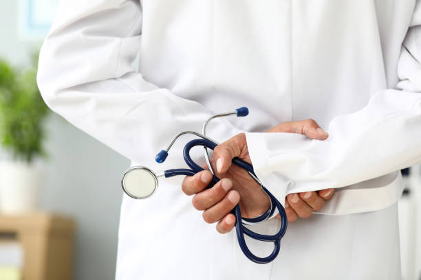 istock Male GP standing with hands over back holding stethoscope 1257894519