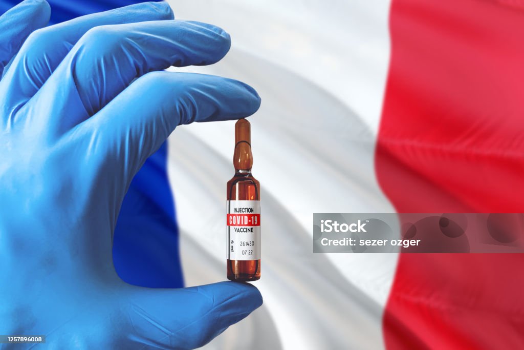 France flag with Coronavirus Covid-19 concept. Doctor with blue protection medical gloves holding a vaccine bottle. Epidemic Virus, Cov-19, Corona virus outbreaking. 2019 Stock Photo