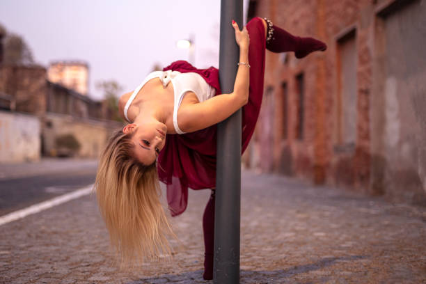 Young woman gracefully performs aerial yoga, suspended from a purple hammock in a bright and airy dance studio