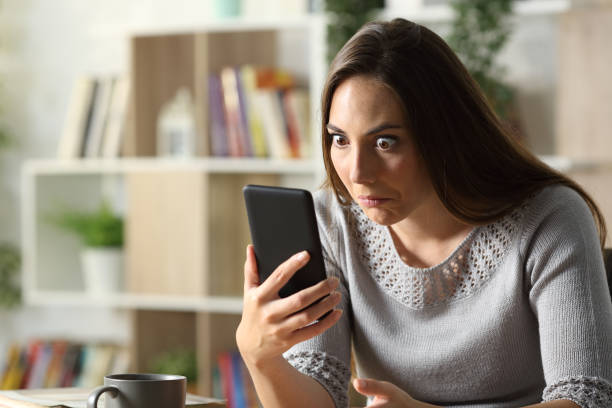 Perplexed woman looking surprised at phone at home Perplexed woman looking surprised at phone at home meme photos stock pictures, royalty-free photos & images