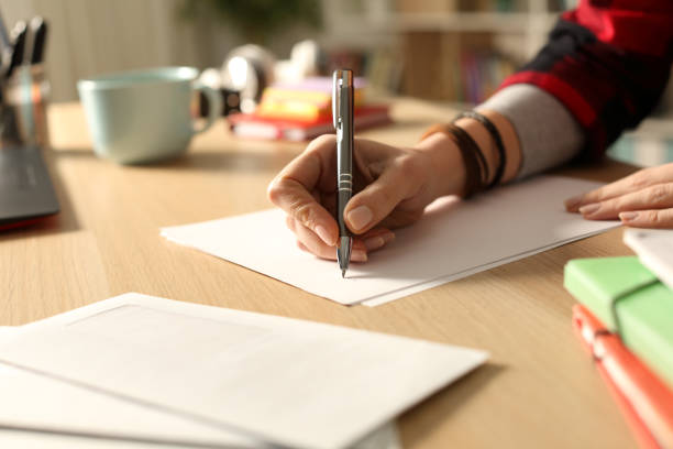 Student hand writing letter at home in the night stock photo