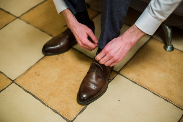 istock man ties the laces on brown shoes 1257903601