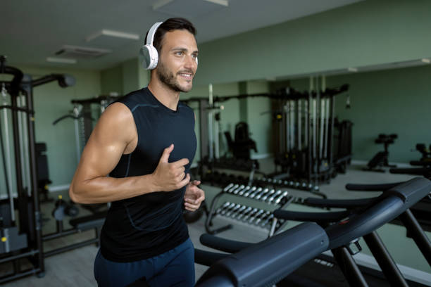 istock Smiling athletic man running on treadmill while exercising in a gym. 1257904992