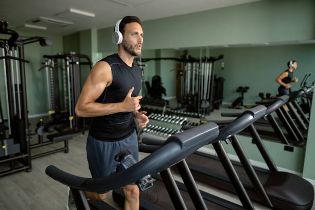 istock Young athletic man running on treadmill in a gym. 1257905015