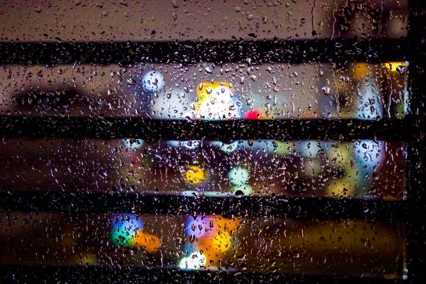 night scene, window glass in raindrops, colorful shop windows lights, blurred background