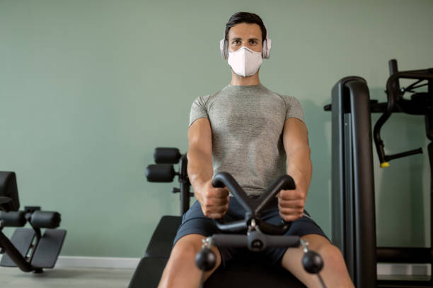 istock Athletic man with face mask having sports training on rowing machine in a gym. 1257905170