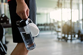 Close-up of athlete carrying protective face mask and bottle pf water in a gym.