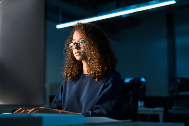 Young businesswoman working on a computer at her office desk at night