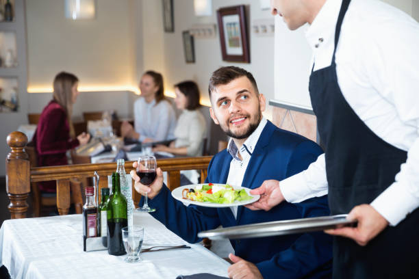 istock Waiter serving delicious salads to handsome young man at restaurant 1257911607
