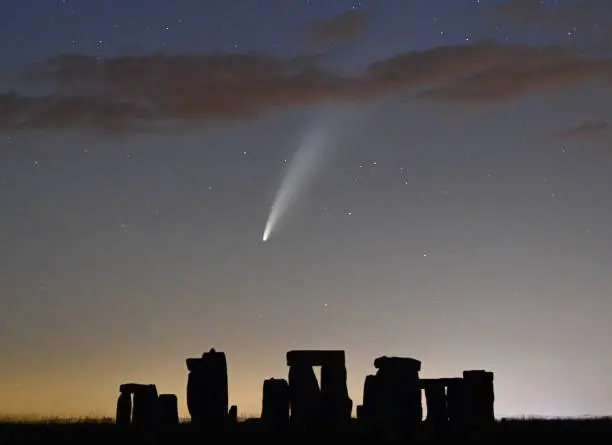 Comet Neowise streams silently above teh ancient stone circle at Stonehenge in Wiltshire, UK