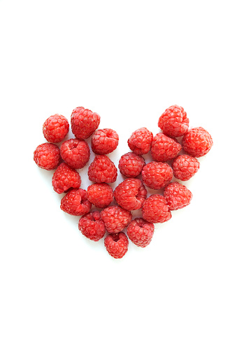 Ripe raspberries heart shaped composition isolated on white background