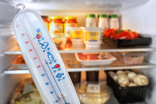 thermometer vor offenem kühlschrank / kühlschrank mit lebensmitteln in der küche gefüllt - temperatur stock-fotos und bilder