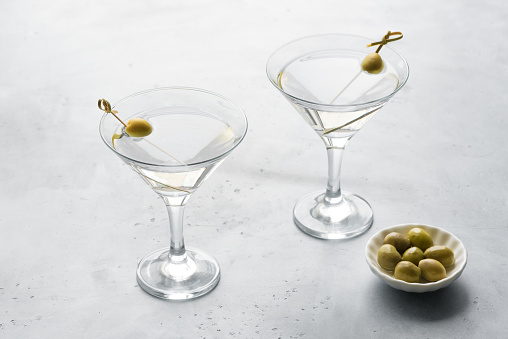 Classic Dry Martini with olives on light background, copy space. Martini vermouth cocktail.