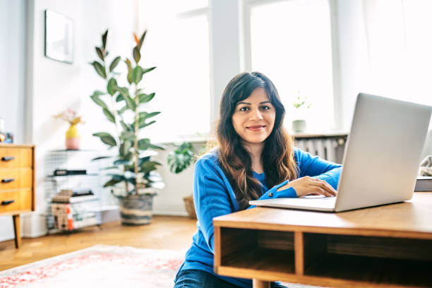istock Smiling woman using laptop in living room 1257914749