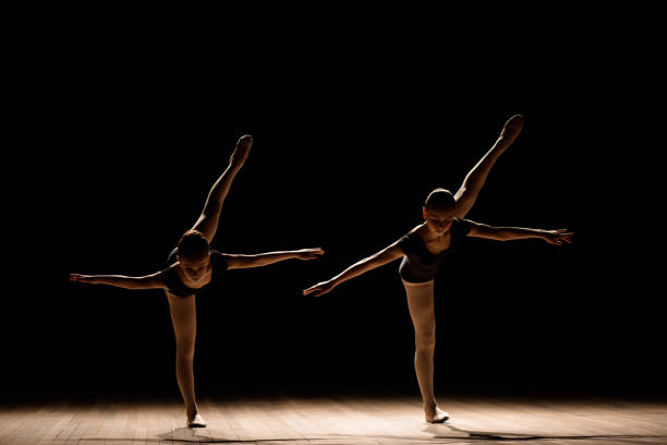 istock Flexible ballerinas stretch on a dark lighted scene 1257918750