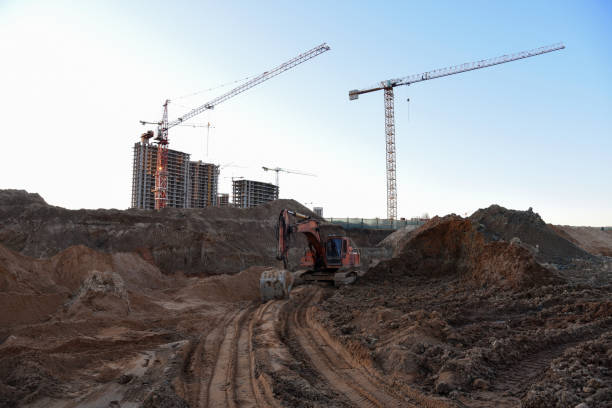 istock Excavator working at construction site on earthworks. Backhoe on road work digs ground. Paving out sewer line. Construction machinery for excavating foundation, loading, lifting and hauling of cargo 1257918759