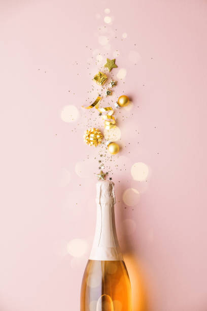 flat lay of celebration. garrafa de champanhe e decoração dourada em fundo rosa - 7651 - fotografias e filmes do acervo