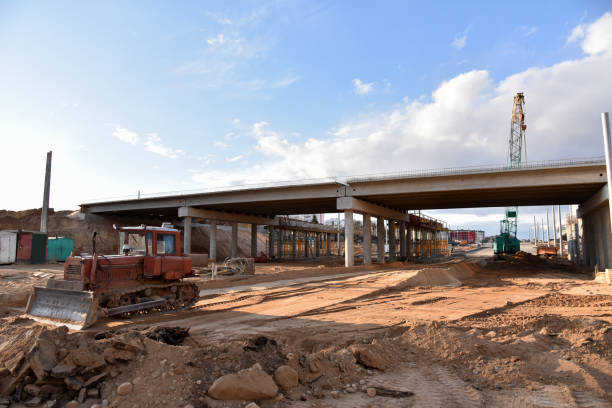 istock Bulldozer working at construction highway ramps and bridgeworks. Roundabout and traffic bridge construction. Road work on traffic highway, road intersection junction and freeway. Bridge project works 1257919954