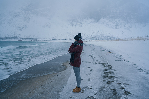Woman walking on seaside in winter on Lofoten island