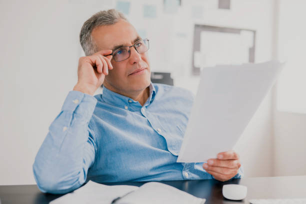 istock handsome gray-haired successful businessman sits in his office studying contract while preparing new business project , money making motivation concept 1257921348