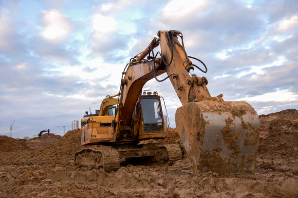 istock Excavator working at construction site. Backhoe digs ground for the foundation and for paving out sewer line. Construction machinery for excavating, loading, lifting and hauling of cargo on job sites 1257922380