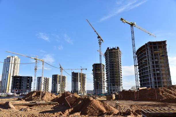 istock Tower cranes in action during construction residential building on blue sky background. Builder workers during formwork and pouring concrete. Crane lifting a concrete bucket and blocks 1257923641