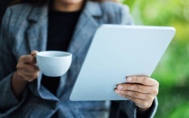 istock a business woman holding and using tablet pc with drinking coffee in office 1257924839