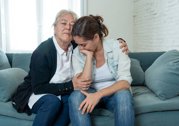 Senior mother comforting adult daughter grieving loss of loved one fighting the Coronavirus. Elderly mother embracing adult daughter suffering from depression. People affected by COVID-19 outbreak. stock photo