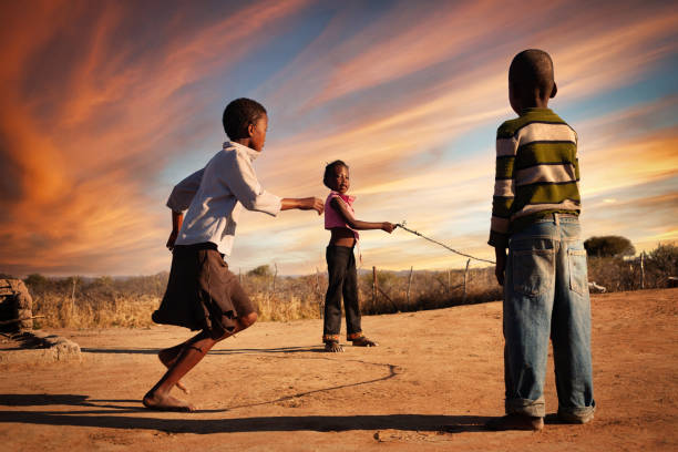 African girls and boy  group skipping rope in the yard in front of the house
