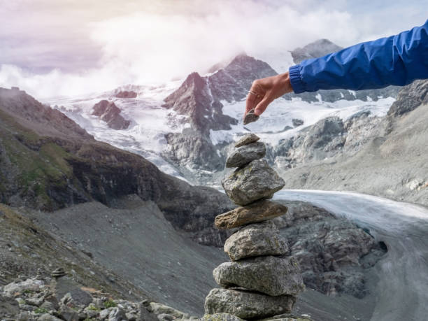 istock View of hand stacking rocks on mountain trail, glacier view 1257939080