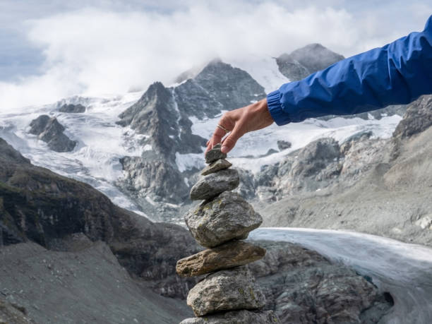 istock View of hand stacking rocks on mountain trail, glacier view 1257939081