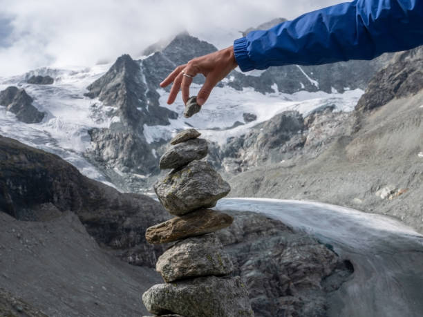 Female's hand stacking rocks against glacier view in Switzerland