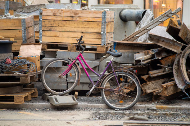 Bike with broken wheel is surrounded by steel, concrete and wood materials.